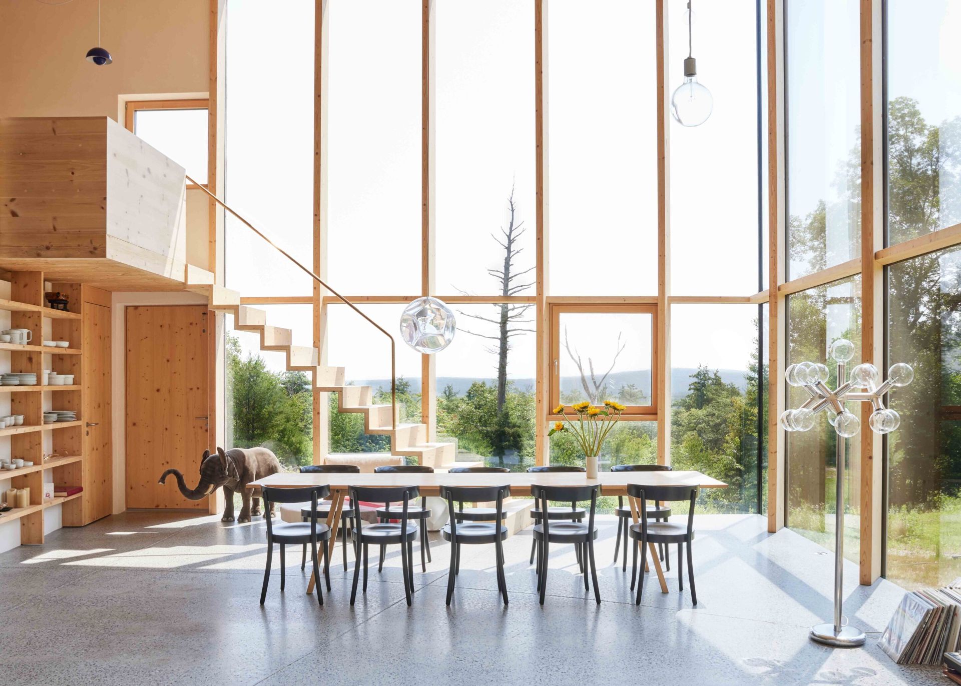3 Casa Cometa Space Rental Interior Dining Room with spruce dining table and black dining chairs and floor to ceiling windows and staircase 3 Casa Cometa Space Rental Interior Dining Room with spruce dining table and black dining chairs and floor to ceiling windows and staircase